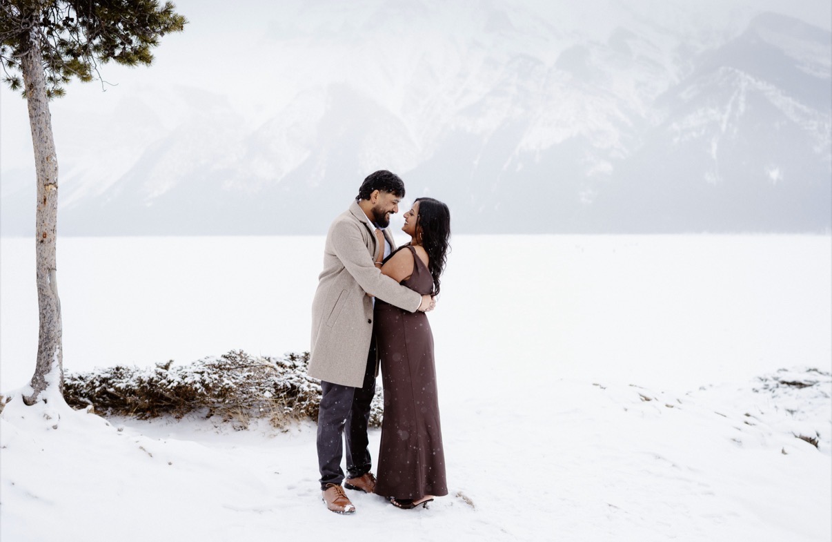 Holding each other on the snowy lakeshore beneath the peaks